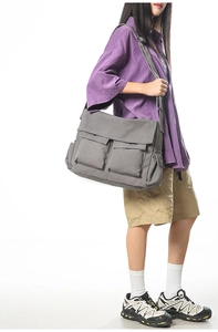 Details einer dunkelgrauen Canvas-Umhängetasche mit großen Taschen und breitem Schultergurt