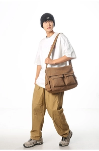 Detail einer großen braunen Canvas-Umhängetasche mit vielen Taschen am männlichen Model