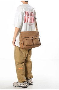 Braune Canvas-Umhängetasche mit großen Taschen am Model präsentiert