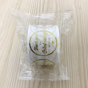 Macro shot of gold foil 'Thank you' stickers on a roll with clear plastic packaging