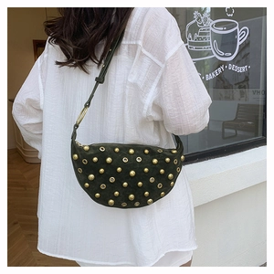 Detail of dark green suede crescent bag featuring golden rivets and eyelets in a bakery scene