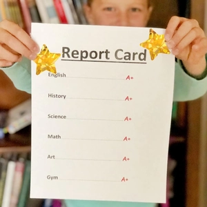 Macro shot of gold holographic star reward stickers on a student's report card