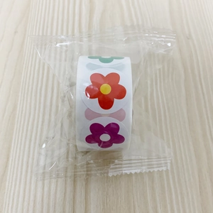 Macro shot of 500-count colorful flower reward stickers roll in transparent packaging