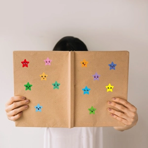 Detailed view of colorful cartoon star stickers on a brown folder held by a model