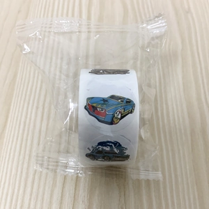 Detailed view of cartoon race car stickers roll on a wooden surface in plastic packaging
