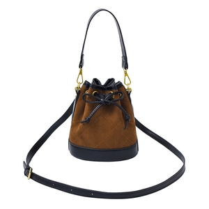Détail du sac seau en daim marron avec finitions en cuir noir et nœud décoratif