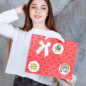 Dettaglio di adesivi tondi 'Be Kind' su sacchetto regalo per premi e sigillatura
