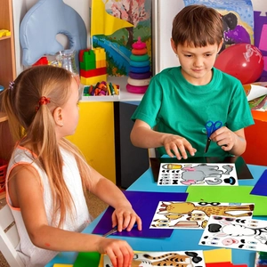 Close-up of children crafting cartoon animal DIY puzzle stickers with safety scissors