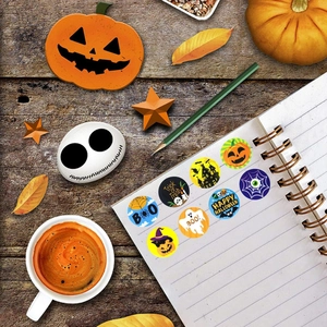 Flat lay of Halloween round stickers with pumpkins and ghosts on a notebook over wood table