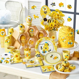 Detailed set of bee-themed party tableware with yellow honeycomb pattern and floral designs