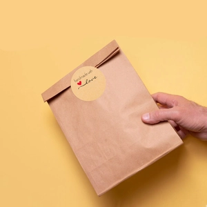 Detail of round kraft paper sticker with handmade with love text on a paper bag seal
