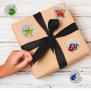 Child opening gift box decorated with holographic marine life stickers on kraft paper