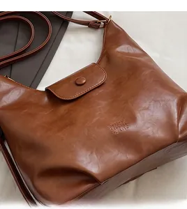 Gros plan d'un cabas en cuir marron foncé montrant la texture fine et la bandoulière