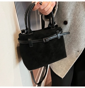 Detail of a mini black frosted leather bucket bag featuring a silver buckle and top handles