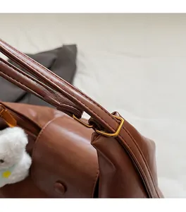 Gros plan détaillé de la boucle dorée sur un sac cabas en cuir marron avec breloque ours