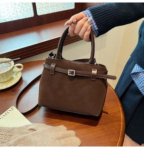 Detailed view of deep brown frosted leather texture and metal buckle on tote bag