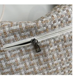 Detailaufnahme des glatten Reißverschlusses an der grau-weiß gewebten Handtasche