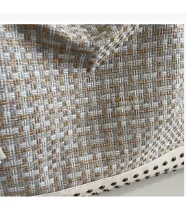 Details der gewebten Tweed-Tasche mit weißem Lederbesatz und Nieten am Taschenboden