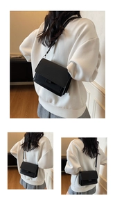 Dettaglio di una borsa a tracolla quadrata nera con fibbia in pelle e logo di moda