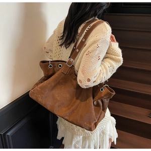 Detail of vintage brown leather tote bag with silver eyelets and adjustable shoulder strap
