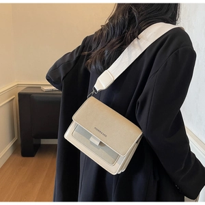 Dettaglio borsa a tracolla beige minimalista con tracolla larga indossata da modella