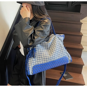 Schicke blau-weiße Tweed-Tragetasche mit Lederbesatz am Modell für einen modischen Alltag