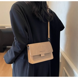 Dettaglio borsa a tracolla marrone con texture opaca e scritta Fashion & Bags