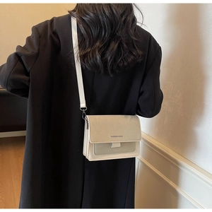 Dettaglio di una borsa a tracolla bicolore minimalista con tracolla larga e logo moda