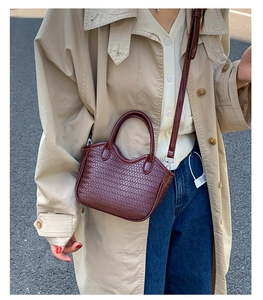 Close-up of a woven wine red bucket bag showing texture and leather strap details