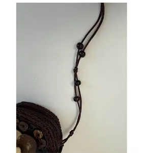 Detail of dark brown woven mini bag with decorative wood beads and shell sequins