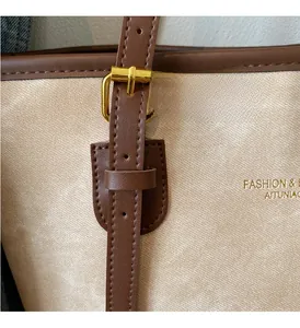 Detail of champagne textured tote bag with golden hardware and brown leather trim