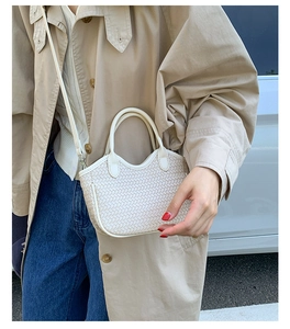 Détail d'un sac bandoulière beige tissé avec poignée ronde pour un style quotidien