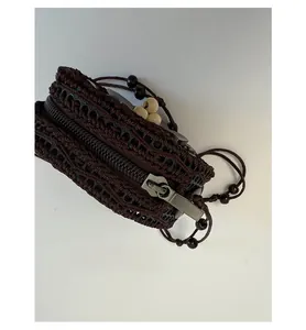 Detailed texture of bohemian hand-woven mini pouch with smooth metal zipper and wooden beads