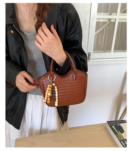 Detail of a brown woven bucket bag with decorative wooden bead tassels for women