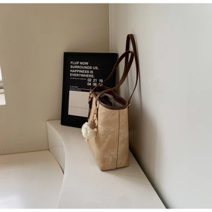 Detail of light khaki tote bag with vintage texture and cute white plush bear pendant