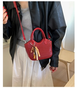Détail d'un mini sac à main tissé rouge avec pompon en perles de bois sur mannequin