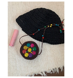 Detail of bohemian round coconut shell bag with colorful sequins and crochet straw hat