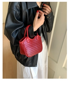 Détail du sac à main en cuir tressé rouge avec texture et poignée supérieure ronde