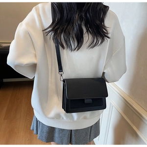 Dettaglio di una borsa a tracolla minimalista in ecopelle nera con ampia tracolla vista retro