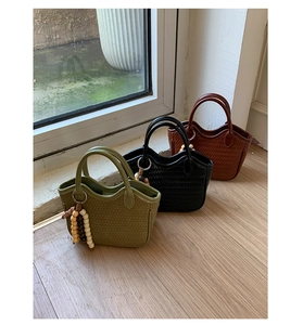 Detail of woven bucket bags in green black and brown with decorative wooden bead handles