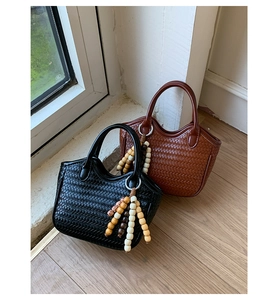 Close-up of woven bucket bag texture in black and brown with wooden bead charms
