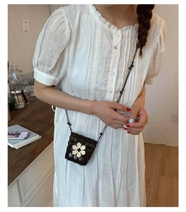 Detail of bohemian mini beaded bag with white flower charm on white lace dress