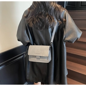 Vista modella di una borsa a tracolla quadrata grigia minimalista con cinturino largo