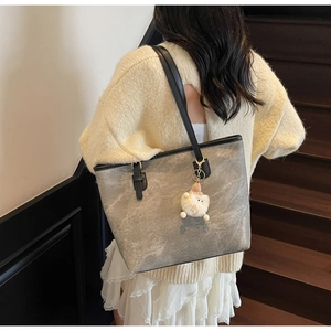 Grey textured tote bag with black handles and a cute plush lamb pendant on stairs