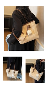 Detail of a large beige tote bag with brown leather handles and a plush sheep pendant
