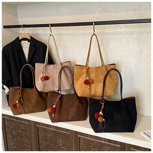 Selection of suede tote bags in various colors with decorative beaded pompom charms