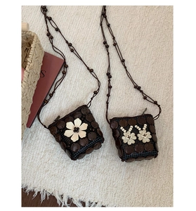Détail du sac boho en noix de coco avec fleur tissée et bandoulière en perles