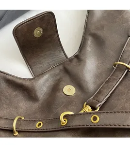 Macro view of vintage brown tote bag showing gold magnetic buckle and textured leather