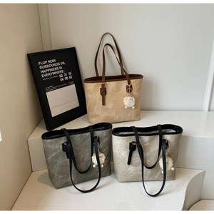 Detailed view of textured tote bags in brown, grey, and beige with cute sheep charms