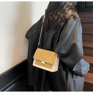 Dettaglio di una borsa a tracolla bicolore zenzero e beige con fianchi a fisarmonica